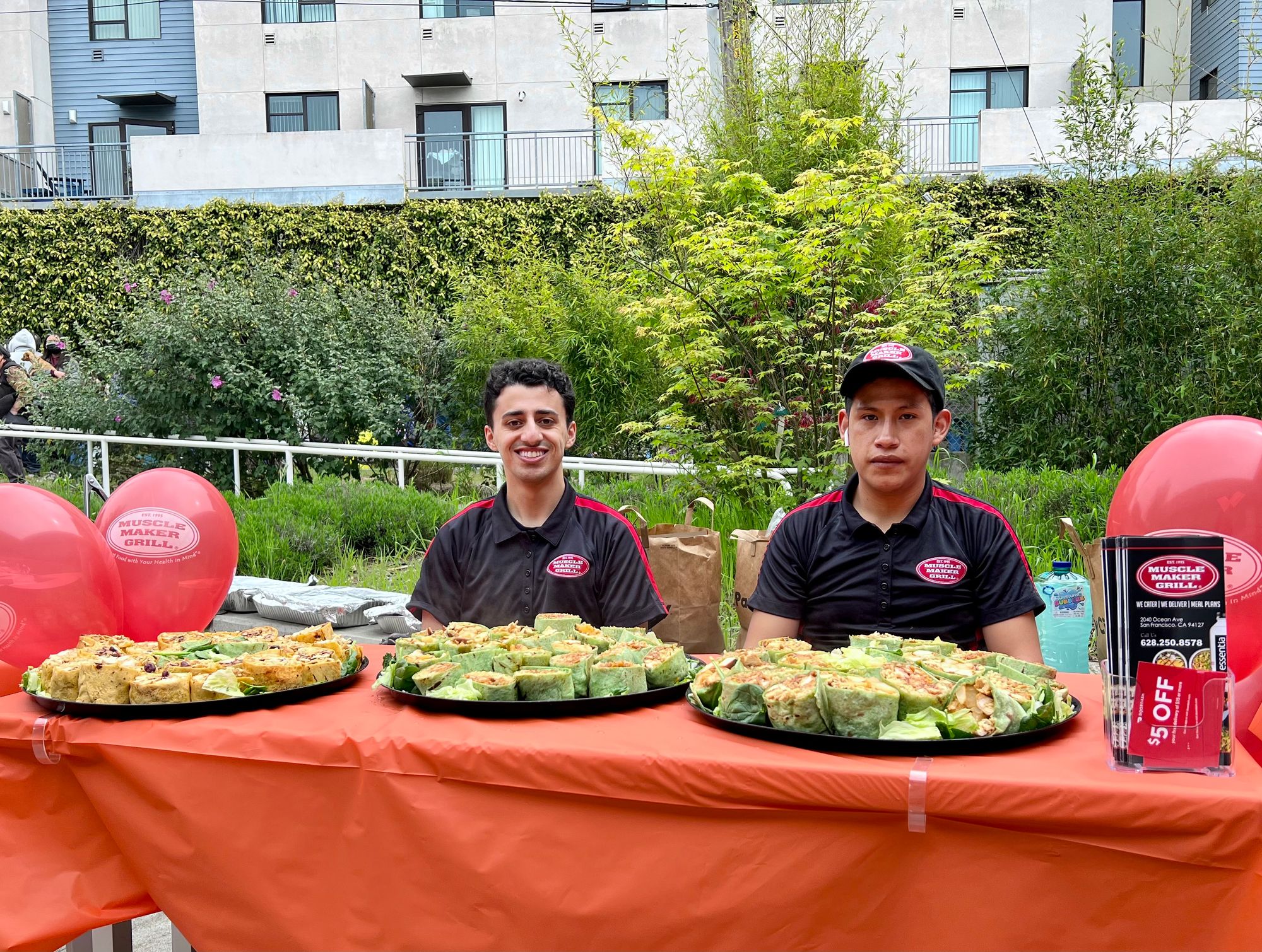 Muscle Maker Grill staff with food platters