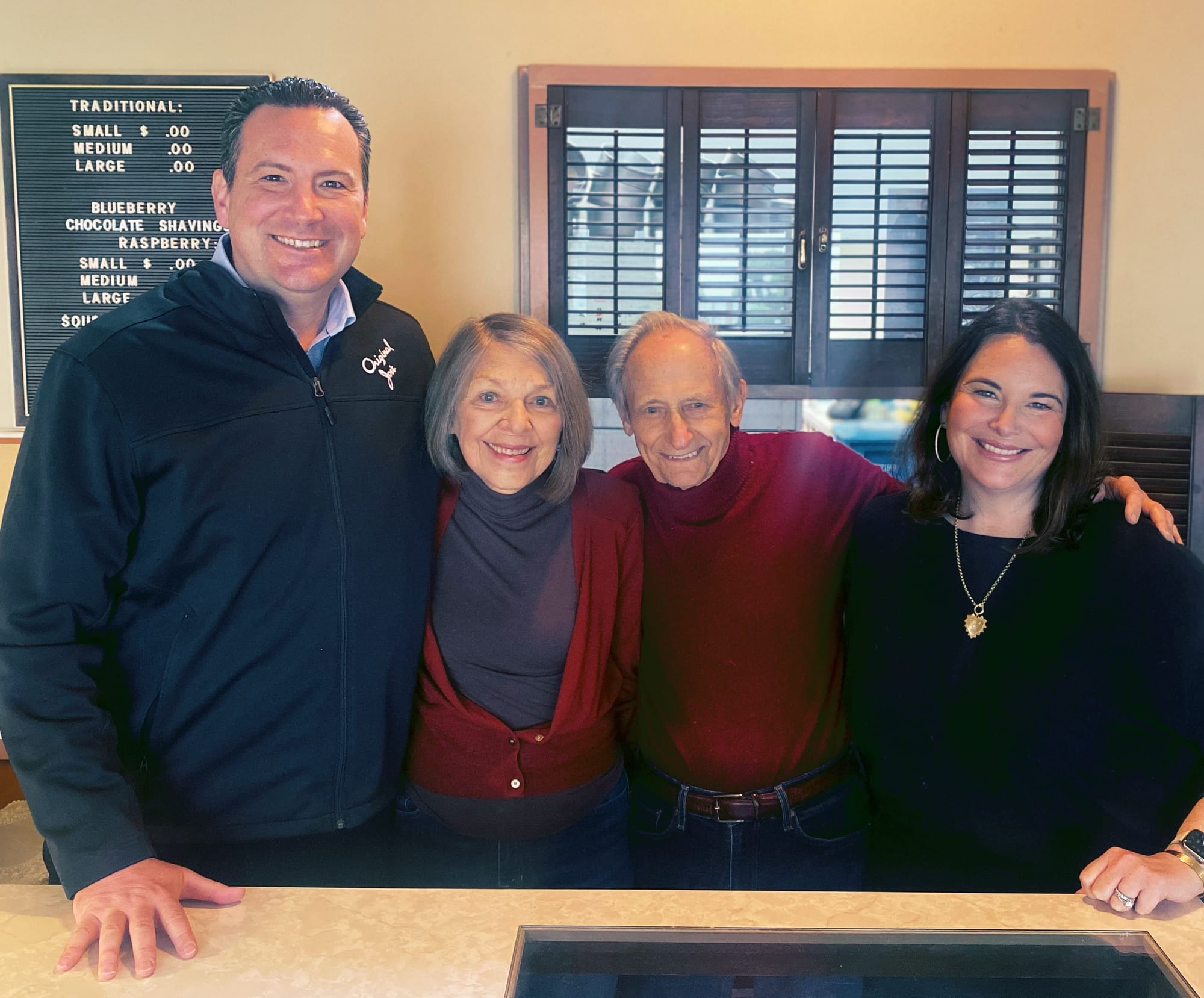 Four people stand behind a counter smiling for a photo.