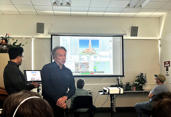 Architect speaks before a group of people looking at a rendering of a building.