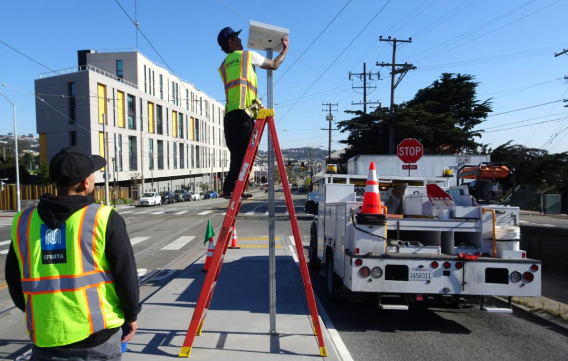 Worker on a ladder installing a solar panel.