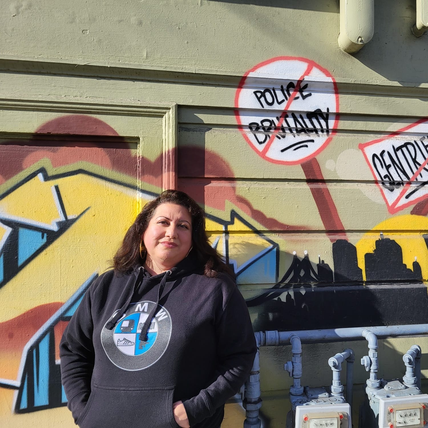 Woman standing in front of a mural for a portrait.