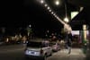 Man walks on sidewalk under string lights.