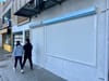 People walk past a storefront.