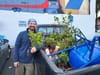 Man holding plants beside a truck in a parking lot.
