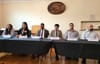 Political candidates seated at two tables with microphones and name placards.