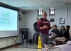 Man in front of a screen talks.
