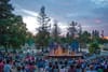  Patrons sit on a hillside at sunset watching a play with a castle backdrop.