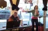 Singer Suzy Q (right) performing with pianist Francisco Rosales (right) in front of window that faces the street.