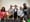 Five people stand behind a table with microphones.
