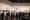 A crowd of casually and black-tie dressed people looking at art pieces on a large white wall.